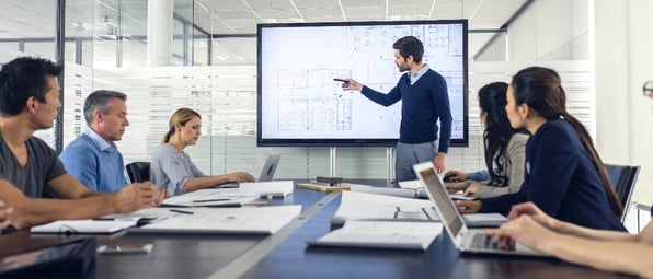 man_pointing_to_screen_in_board_meeting